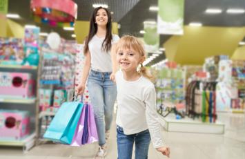 girl-keeping-hand-mom-running-forward-toy-store